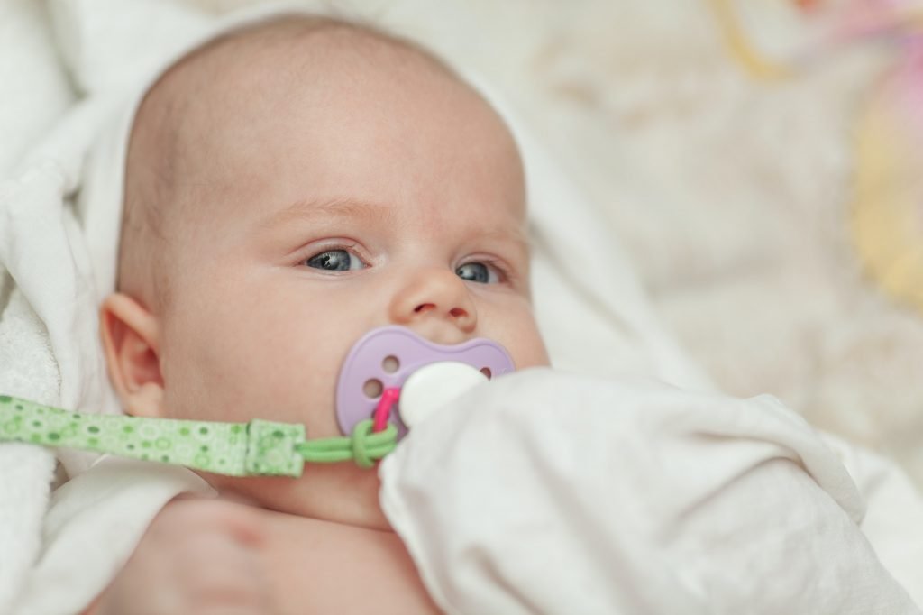 A portrait of a baby boy with a baby dummy